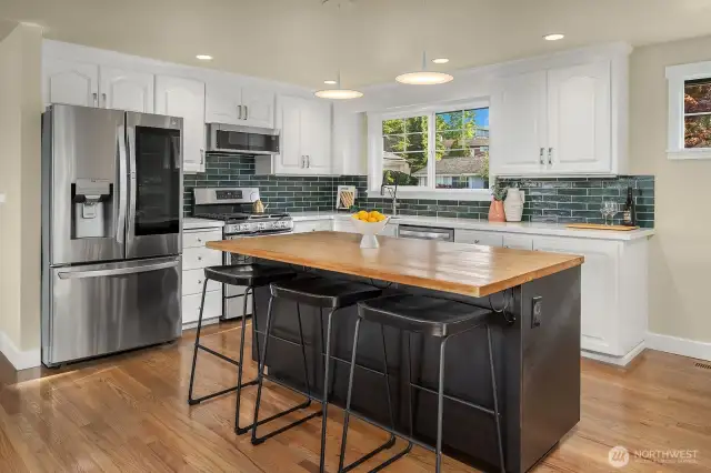 Kitchen refreshed in 2025, with new quartz countertops and ceramic tile backsplash, refinished cabients. refinished butcher block counter and newer stainless steel appliances.