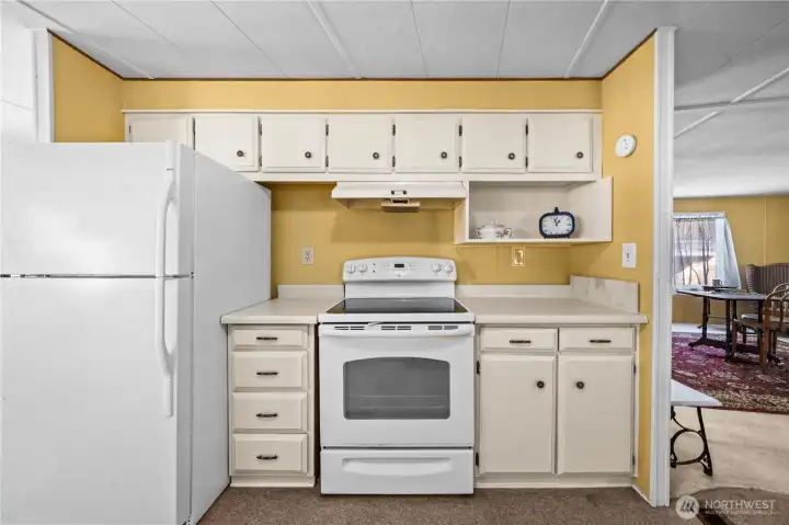 Efficient eat-in kitchen layout with white appliances and generous storage throughout.