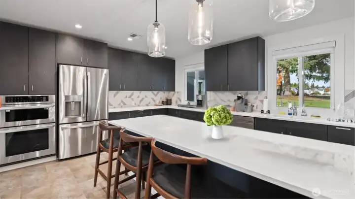 Modern, state-of-the-art clubhouse kitchen with large island and premium appliances for resident events and activities.   (photo virtually staged w/flower centerpiece)