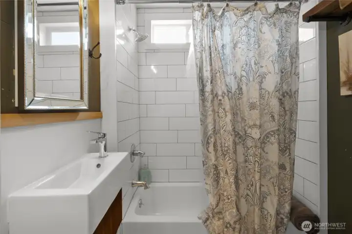 Main floor restroom with custom tile work, large bath tub and original wood accents.