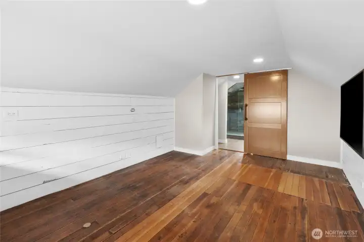 Another view of upstairs primary bedroom with quaint hardwood floors and shiplap wall accents.