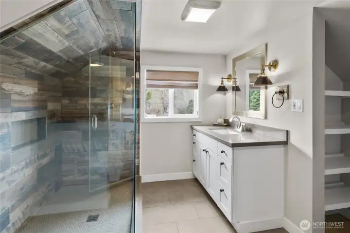 Take in lavish primary bathroom w/ tile floors, custom shower, quartz counter and linen closet.