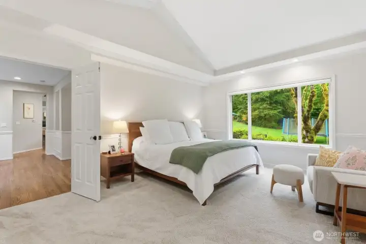 Luxurious main floor primary suite offers a tranquil escape with serene backdrop.