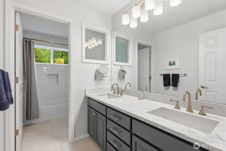 The updated hall bath features dual undermount sinks, slab granite counters, and timeless subway tile extending to the ceiling.