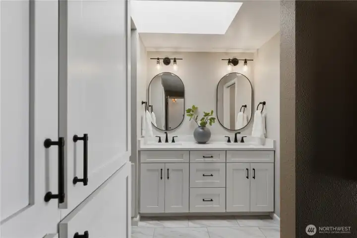The updated, spa-like primary bath features dual sinks, designer mirrors, and tile flooring. The updated, spa-like primary bath features dual sinks, designer mirrors, and tile flooring.