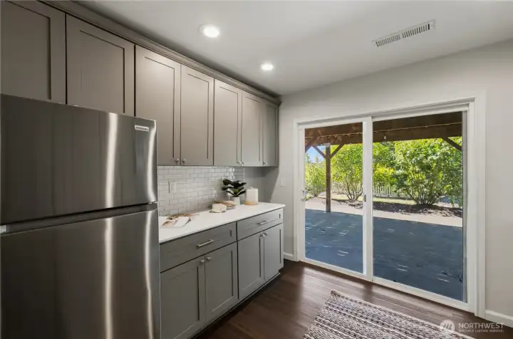 A second fully updated kitchen features quartz countertops, a tile backsplash, and new appliances, including an induction oven. Patio access is just steps away. A second fully updated kitchen features quartz countertops, a tile backsplash, and new appliances, including an induction oven. Patio access is just steps away.