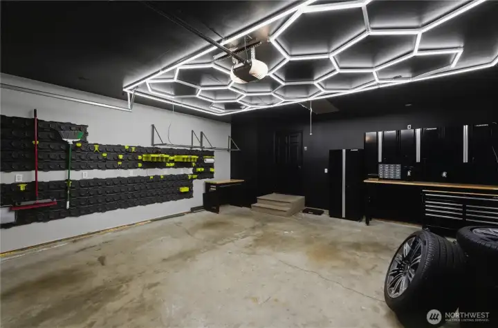 The garage is a dream workspace, featuring a hexagon lighting grid and extensive tool storage. The garage is a dream workspace, featuring a hexagon lighting grid and extensive tool storage.