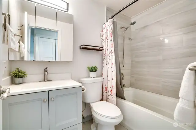 The full guest bath has been updated with a new vanity, toilet, and tile surround for the bath and shower combination.