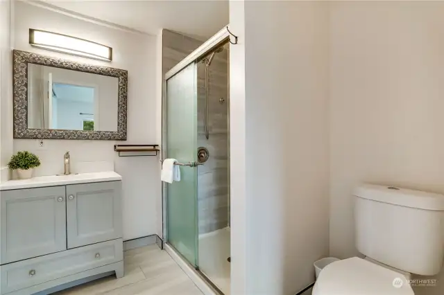 This refreshed ensuite bathroom features a large, fully tiled, walk-in shower with glass doors, updated vanity and fixtures and easy to maintain flooring.
