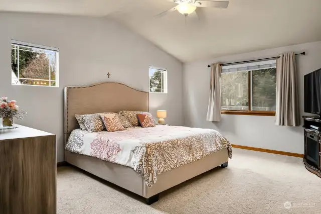 Spacious primary bedroom with vaulted ceiling, ceiling fan, and plenty of natural light.