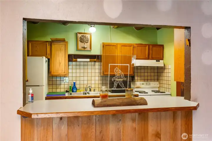 The open pass-through keeps the kitchen connected to the living areas, making gatherings easy. Handcrafted wood cabinets, tiled backsplash, and rustic accents blend with the quirky Bigfoot artwork, reminding you of the home’s unique story.