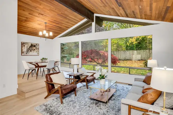 Open-Concept Living Room, Soaring ceilings and rich wood accents create a warm, Northwest feel. Floor-to-ceiling windows frame the lush, private backyard—perfect for relaxing or entertaining.