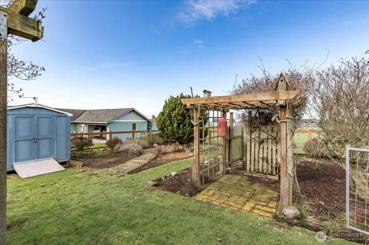Garden shed in backyard and arbor.