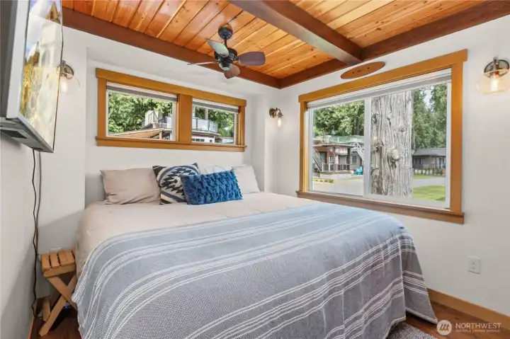 Main-level bedroom with wood ceiling detail and natural light. Main-level bedroom with wood ceiling detail and natural light.