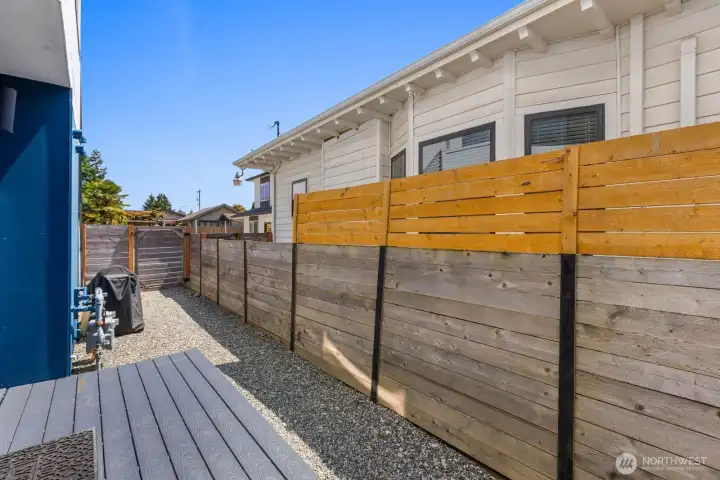 Fenced side yard with a small deck and low-maintenance gravel area. Fenced side yard with a small deck and low-maintenance gravel area.