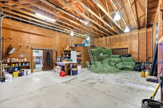 End garage bay is uninsulated and features pull-through doors and small storage space currently used as tack room.