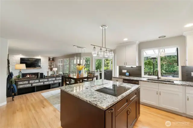 Chef’s dream kitchen with oversized island, glass pendant lighting, granite counters, and open sightlines to the dining and living spaces—ideal for entertaining.