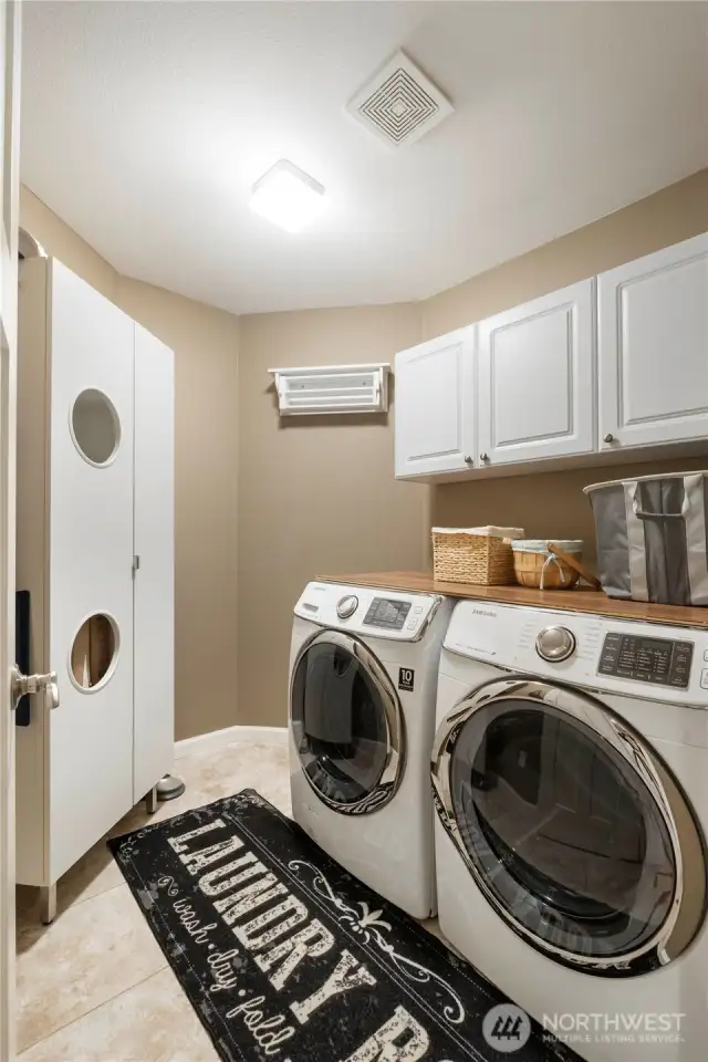 Laundry Room – Modern appliances, upper cabinets, and a clever wall-mounted drying rack.