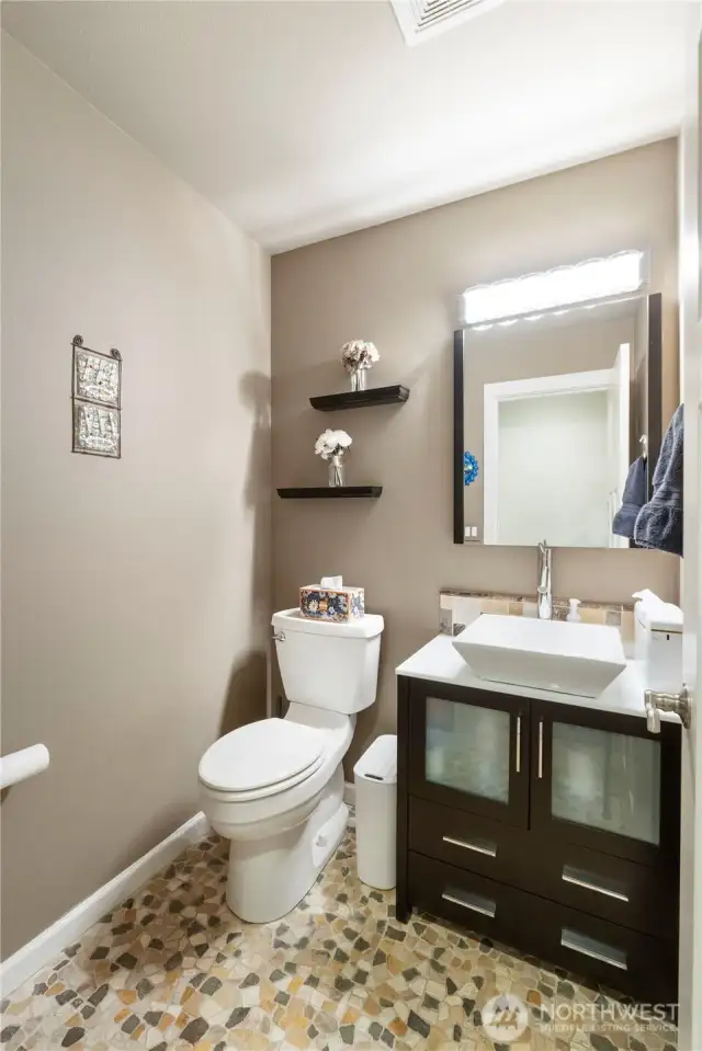 Main Floor Half Bath: Chic and modern powder room with custom vessel sink, designer vanity, and stone mosaic flooring—perfectly positioned for guest use on the main floor.