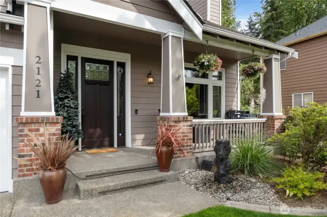 Front Porch – Inviting curb appeal with brick columns, planters, and hanging baskets.
