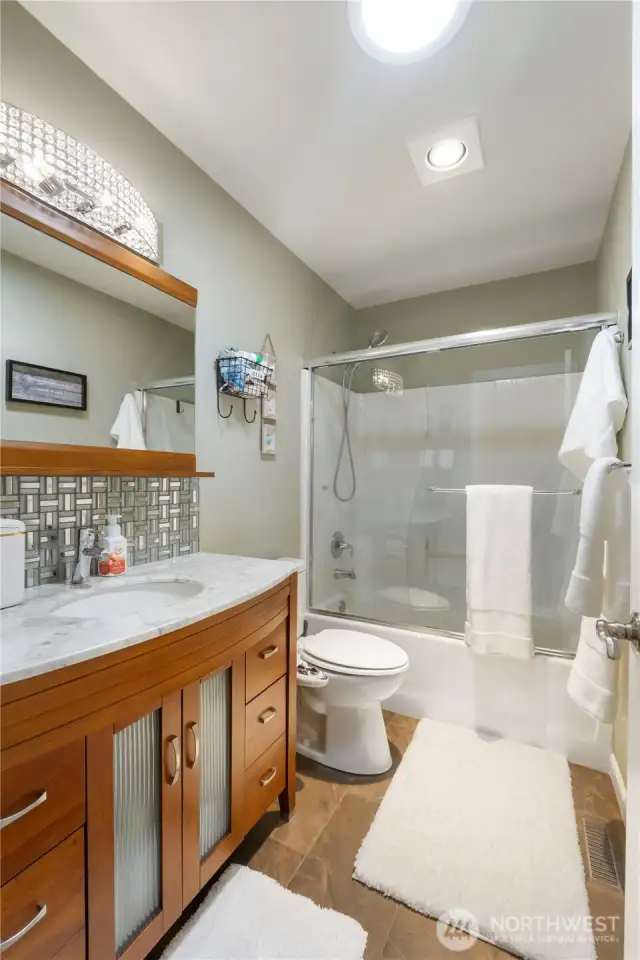 Style meets sparkle. This charming full bath features designer finishes, a marble-top vanity, and a twinkle in its eye (literally—that light fixture!).