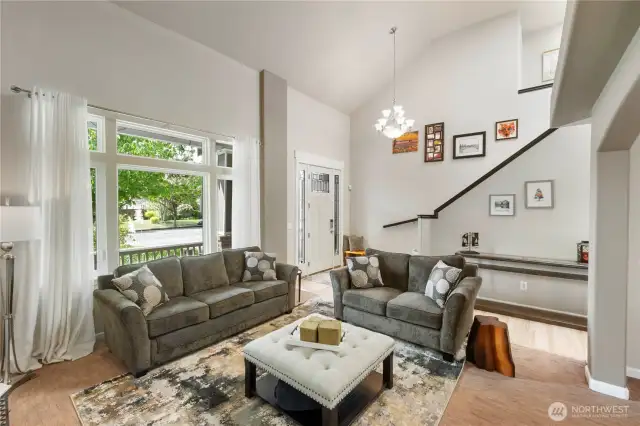 Spacious and sunlit great room seamlessly connects to the dining and kitchen areas, featuring custom shutters, beautiful hardwood floors, and cozy fireplace ambiance.