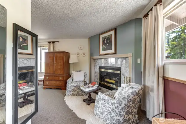 Reading/Sitting room with cozy wood burning fireplace at the top of the stairs leading to upstairs primary bedroom!