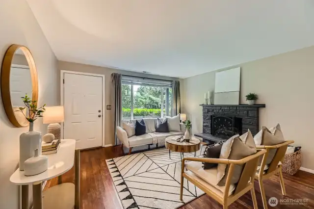A beautiful and cozy living room, and a beautiful fireplace anchoring the room, hardwood floors and new paint
