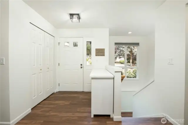 Entry with closet. LVP stair treads with white risers. Large fixed window with ledge at landing; includes remote-controlled grey shades.