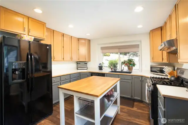 Uppers are wood-look finish (8 total), and lowers are grey wood (6 total) with 9 pull-out drawers. Additional built-in wall storage with two double-door shelving units. Island includes 2 steel shelves and wood top.