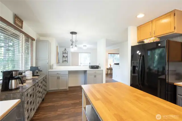 Black Bosch Ascenta dishwasher, stainless and black LG propane range with oven, NuTone stainless vent hood, black LG double-door refrigerator with water/ice dispenser. Black single-basin sink with stainless faucet and soap pump.