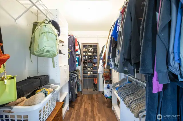 Primary closet with built-in shelving and cabinets on both sides, and wire shelving with hanging storage. Attic access located in the primary closet.