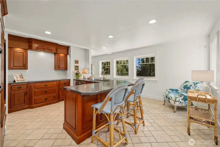 True coastal style kitchen with custom cabinetry, a custom cooktop hood accenting the living area wood floors found throughout the home.
