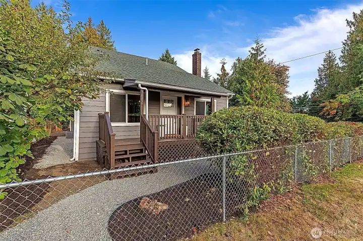 Reimagined and new covered front porch with access to gravel pathway around home. New gutters, insulation and vapor barrier.  Fully fenced with mature and new landscaping.