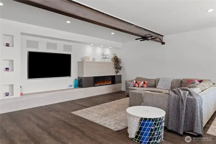 Lower level rec room features a gas fireplace and large TV with wired speaker system. You can see the structural steel beam that was added to open up the floor plan upstairs and downstairs.