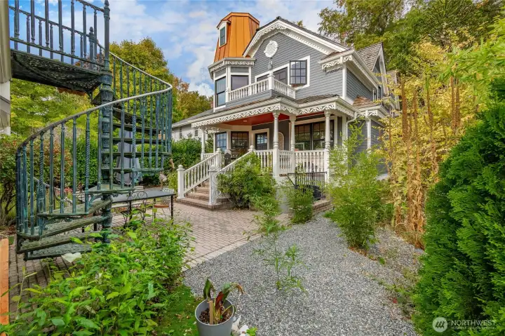 Rear of the home. Covered porch off the back with a deck off the primary above. Spiral staircase in the foreground leads to the Accessory unit above the garage.