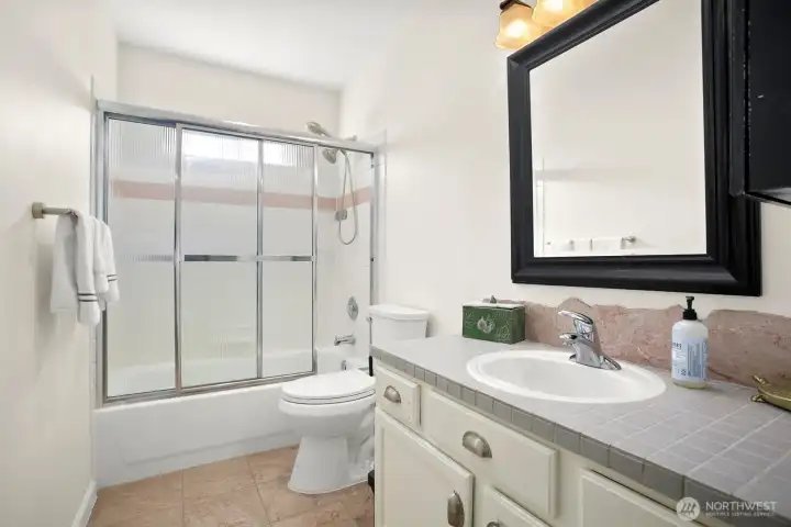 Main full bathroom with tiled countertop and shower