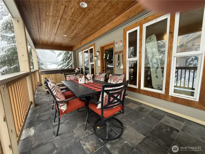 Main level deck off of the living area with large table and hot tub.
