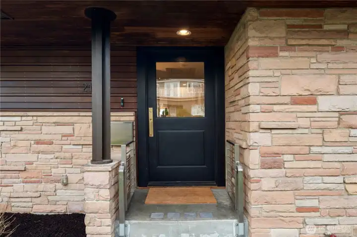 A striking modern entry framed by stone and wood accents, setting the tone for the thoughtfully updated interiors within.