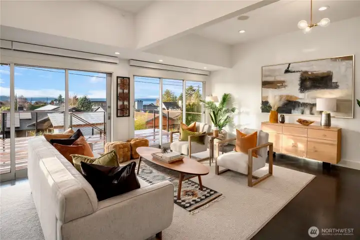Sun-drenched living spaces open to the deck through walls of glass, capturing Olympic Mountain views beyond.