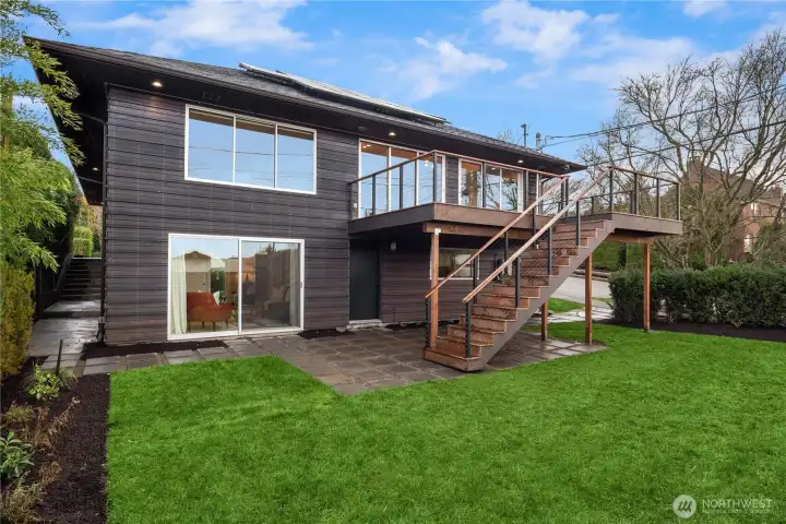 A beautifully designed backyard with lush lawn and an elevated deck, offering seamless indoor-outdoor living and space to relax or entertain.