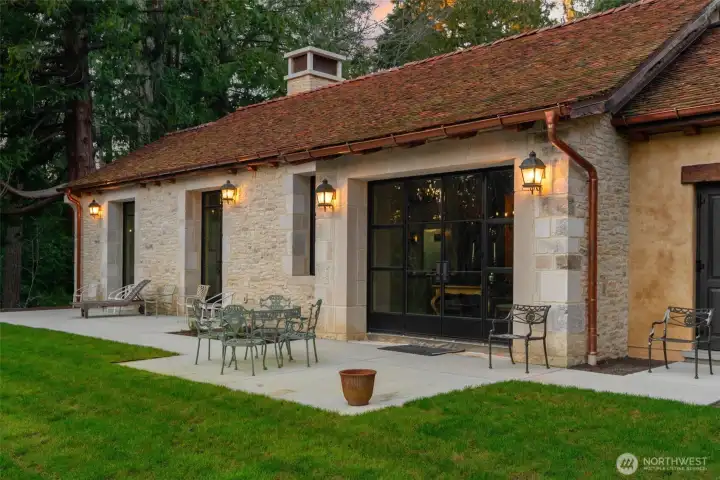 The rear patio unfolds in classic European fashion, framed by natural stone and designed for effortless indoor-outdoor living.