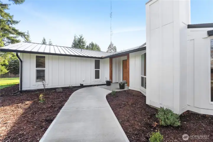Beautiful front entry to home, freshly poured concrete pathway flows seamlessly into living space. Covered entry with beautiful millwork.