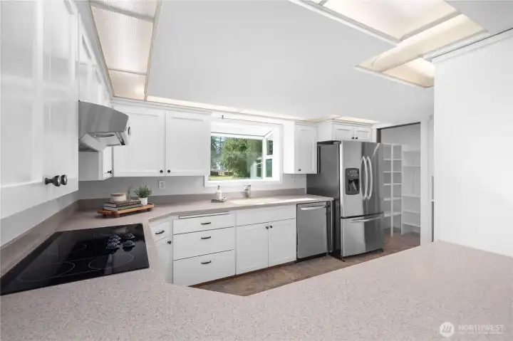 Looking into kitchen from lounge space off dining room, you are greeted by an open concept kitchen with abundance of natural light, lots of prep space, full size walk in pantry, and stainless steel appliances. Entertainers dream.