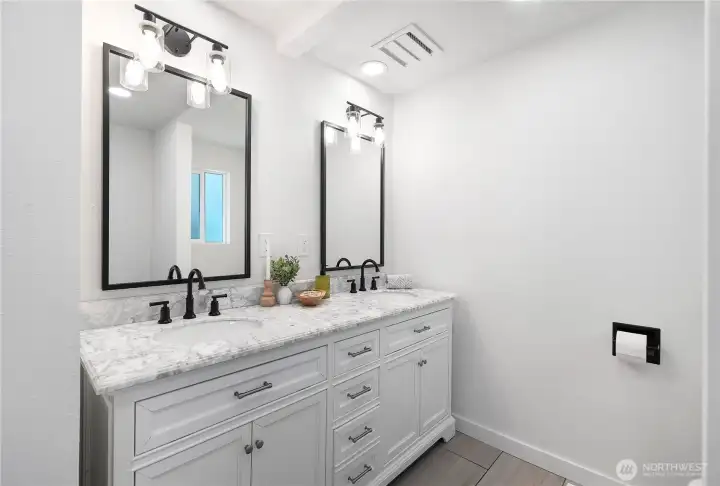 Double vanity in your en suite primary bathroom. Marble countertops with newly updated lighting and fixtures, tile flooring and walk in shower.