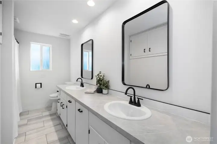 Full bath lies down middle of hallway conveniently located between all bedrooms. Double sinks with new fixtures and recessed lighting. Abundance of storage with built in laundry hampers in vanity.