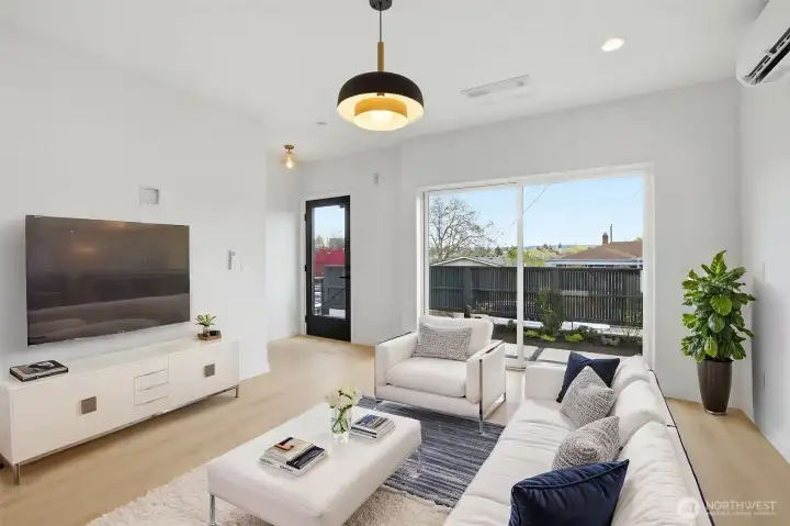 Bright open-concept living room with large sliding doors, natural light, mini-split heating and cooling, and seamless indoor-outdoor flow.