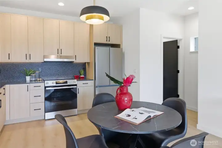 Custom penny tile backsplash, stainless steel appliances, and custom lighting. Powder soom and large storage closet off the main level in the background.