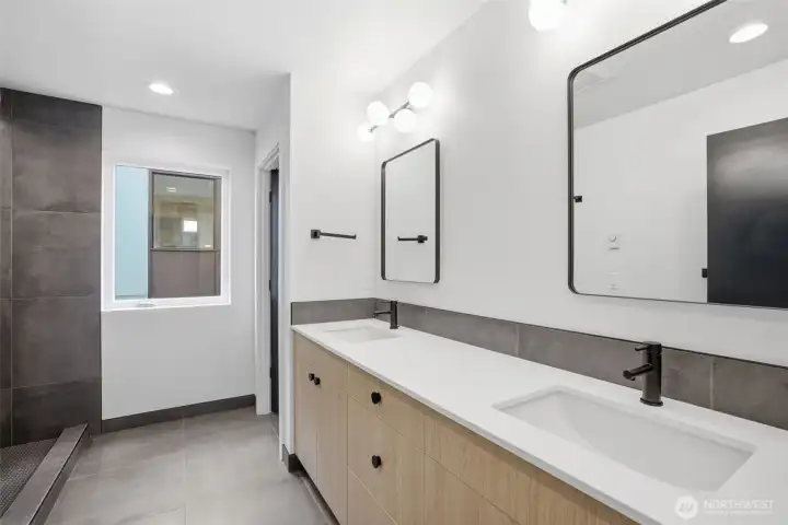 Spa-inspired primary bathroom with double vanity, quartz countertops, designer tile shower, modern fixtures, and luxury new construction finishes.