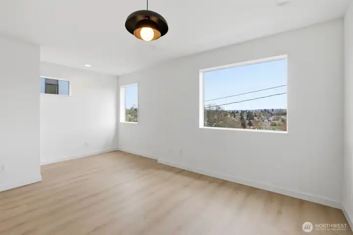 Large primary suite on the upper level with views extending over the nearby park. Custom lighting throughout. A space for a desk or sitting area.